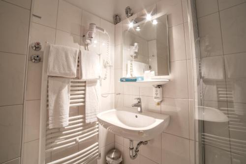 a white bathroom with a sink and a shower at City Hotel Hannover in Hannover
