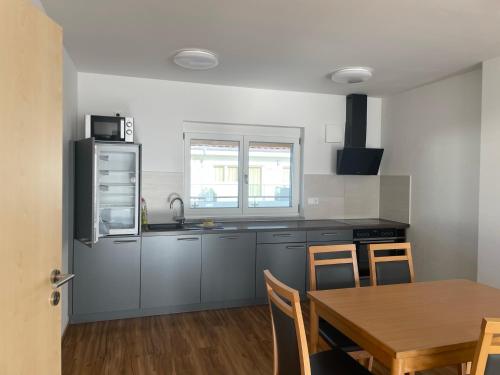 a kitchen with a table and a sink and a refrigerator at Pension RoBi in Harthofen