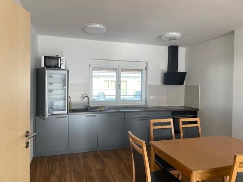 eine Küche mit einem Tisch, einer Spüle und einem Kühlschrank in der Unterkunft Pension RoBi in Harthofen