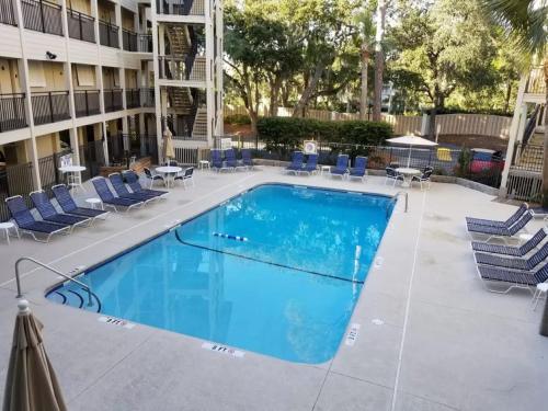 a swimming pool with blue chairs and a building at Beachfront Condo with Ocean View in Hilton Head Island