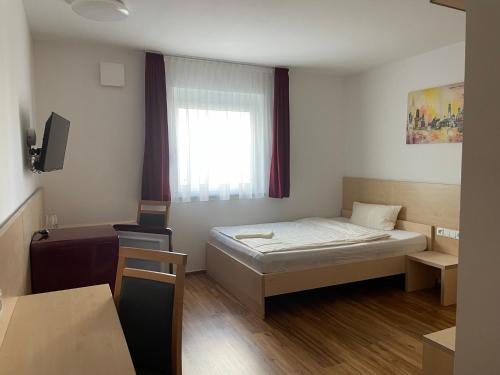 Kleines Zimmer mit einem Bett und einem Fenster in der Unterkunft Pension RoBi in Harthofen