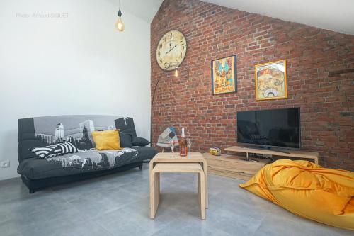 a living room with a couch and a brick wall at Gîte de la Madeleine in Landelies