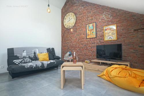 uma sala de estar com um sofá e uma parede de tijolos em Gîte de la Madeleine em Landelies