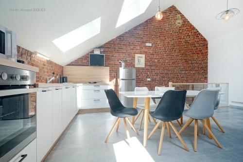uma cozinha com uma mesa e cadeiras e uma parede de tijolos em Gîte de la Madeleine em Landelies