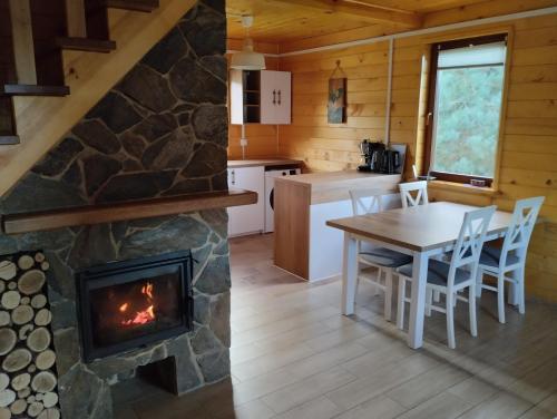 uma cozinha e sala de jantar com lareira num chalé de madeira em Chabrowe Roztocze 