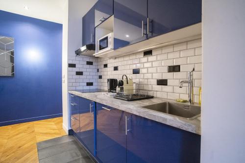 une cuisine avec des armoires bleues et un évier dans l'établissement Apartment near Montmartre, à Paris