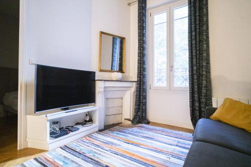 un salon avec une télévision et un canapé dans l'établissement Apartment near Montmartre, à Paris