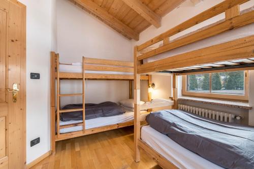 2 letti a castello in una camera con soffitti in legno di Casa Titol Ami a Pozza di Fassa