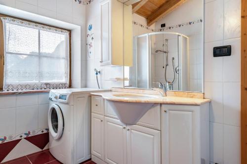 a bathroom with a sink and a washing machine at Casa Titol Ami in Pozza di Fassa