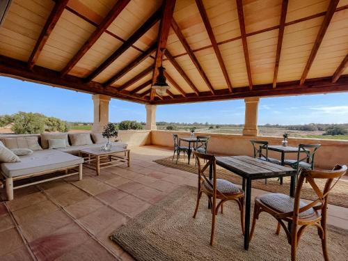 a patio with a couch and tables and chairs at Finca Gomera - Agroturismo Hotel in Cala Pi