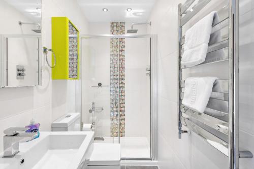 ein weißes Bad mit einer Dusche und einem Waschbecken in der Unterkunft Penthouse 16 At The Beach in Beesands