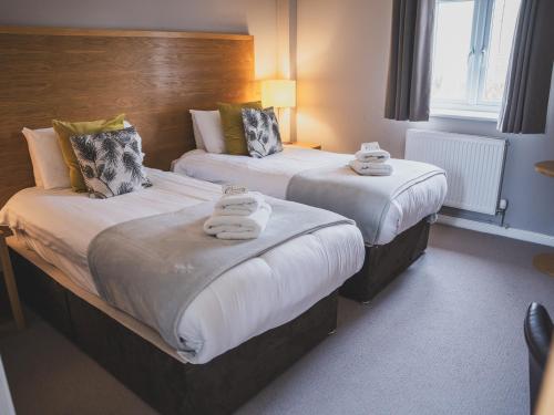 two beds in a hotel room with towels on them at Crossways in Wells