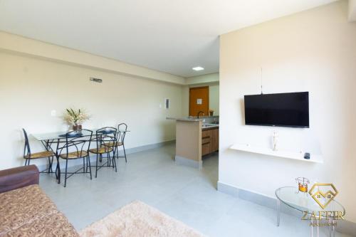 a living room with a table and chairs and a tv at Zaffir Apartamento in Cuiabá