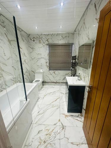 a marble bathroom with a tub sink and a toilet at KNIGHTSBRIDGE COURT in Horninglow