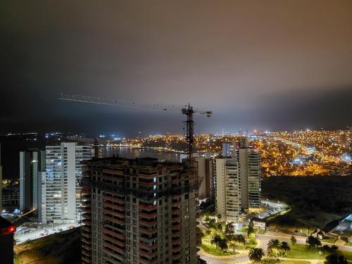 a view of a city at night with a crane at Depto 2D/2B vista mar 6 personas in Concón