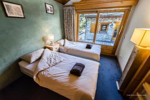 Duas camas num pequeno quarto com uma janela em Joli Chalet Savoyard em Val dʼIsère