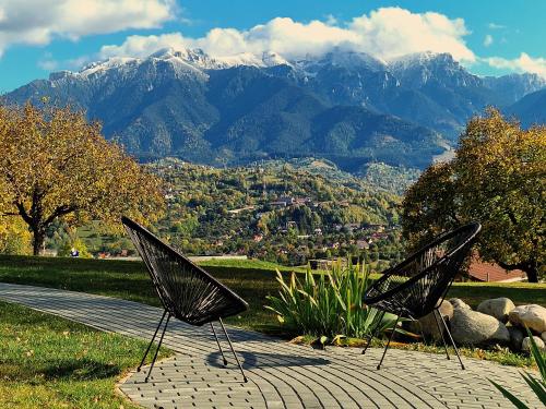 two chairs sitting on a walkway with mountains in the background at Plai din Bran in Bran