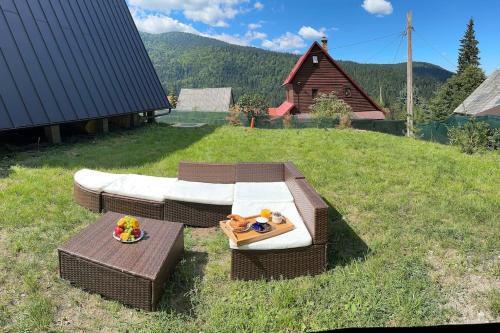 a wicker table and chair on a grass field at Macko’s cabin in Băile Tuşnad