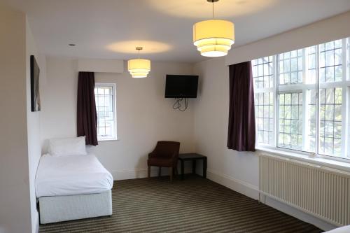 a room with a bed and a tv and windows at Fairway Inn in Manchester