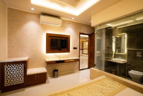 TV y baño con aseo y lavamanos. en Hotel RR 62, en Jaipur