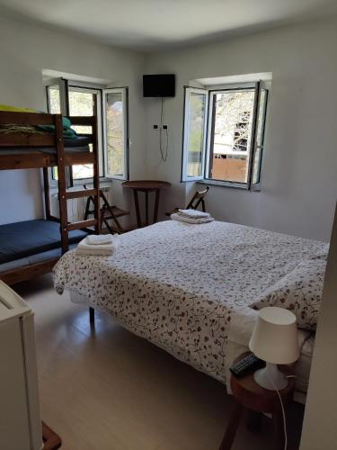 a bedroom with a bed and two windows at Agriturismo Munarin Caterina in Mioglia