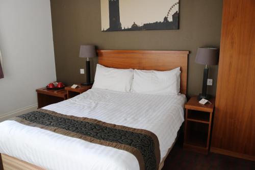 a large bed in a hotel room with two night stands at Fairway Inn in Manchester
