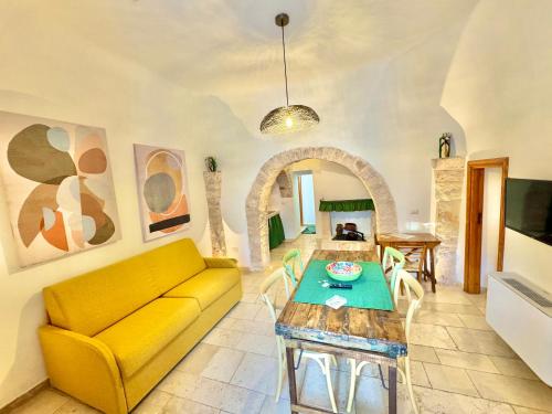 a living room with a yellow couch and a table at Trulli Fenice Alberobello in Alberobello