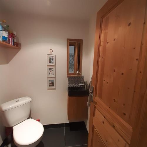 une salle de bain avec toilettes et porte en bois dans l'établissement Appartement Chamonix Bossons, à Chamonix-Mont-Blanc