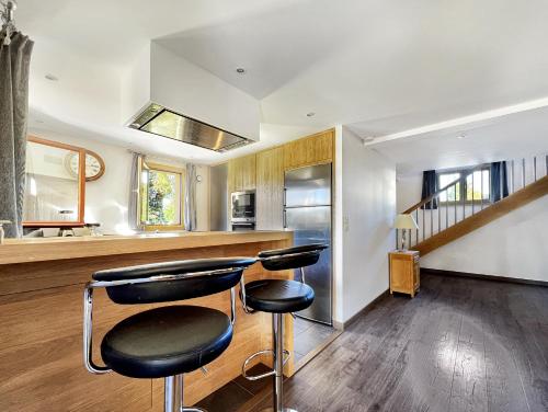 une cuisine avec deux tabourets de bar devant un comptoir dans l'établissement Chalet Haut Standing à proximité du centre (CH228), aux Carroz d'Arâches