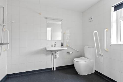 a white bathroom with a toilet and a sink at Lytton Tree Lodge Near Southwold in Reydon