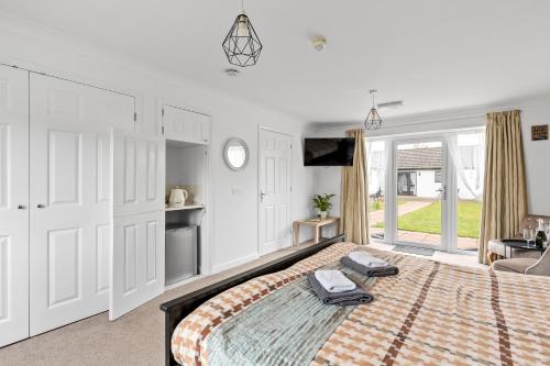 a white bedroom with a large bed and a tv at Lytton Tree Lodge Near Southwold in Reydon