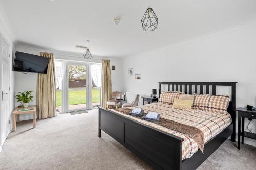 a bedroom with a large bed and a tv at Lytton Tree Lodge Near Southwold in Reydon