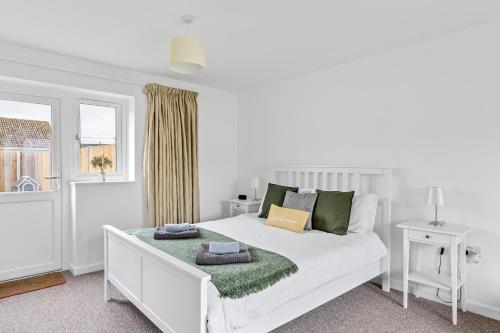 a white bedroom with a white bed and a window at Lytton Tree Lodge Near Southwold in Reydon