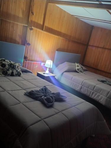 a room with two beds with a robe on it at the wooden house choquequirao in Cachora