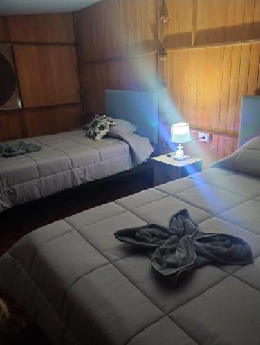 a room with two beds and a lighted room with at the wooden house choquequirao in Cachora