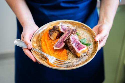 a person holding a plate of food with meat on it at La Pépite in Margut
