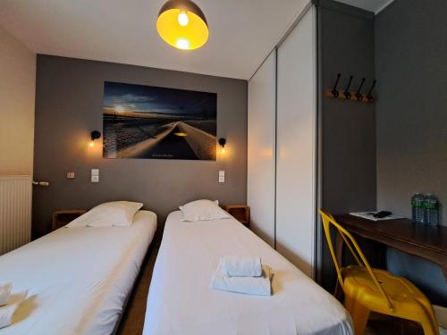 two beds in a room with a picture on the wall at Hôtel Les Mouflons in Le Mont-Dore