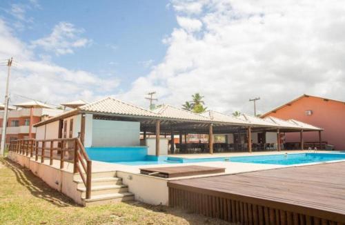 a house with a swimming pool and a wooden deck at Cond Praia Da Perola - Apt Rosa 7 in Ilhéus