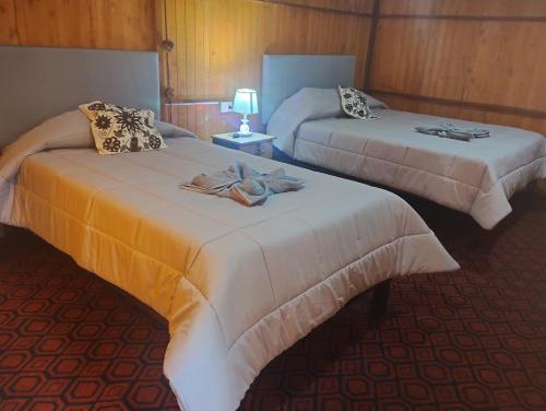Dos camas en una habitación de hotel con toallas. en the wooden house choquequirao, en Cachora