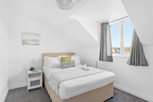 a white bedroom with a bed and a window at Chandlers Walk modern comfy family home in Exeter in Exeter