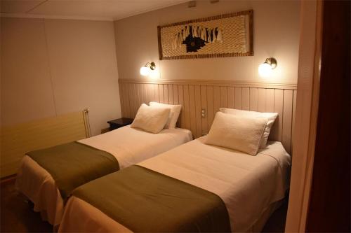 duas camas num quarto de hotel com luzes na parede em Temukistan em Temuco