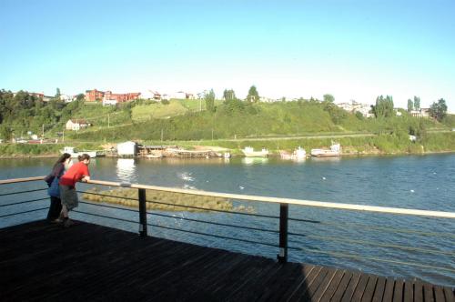 two people standing on a pier looking at the water at Palafito 1326 Hotel Boutique Chiloé in Castro