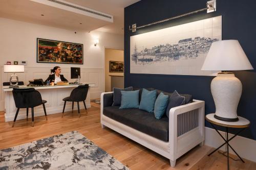 a woman sitting at a desk in a living room with a couch at Dona Maria Hotel in Figueira da Foz