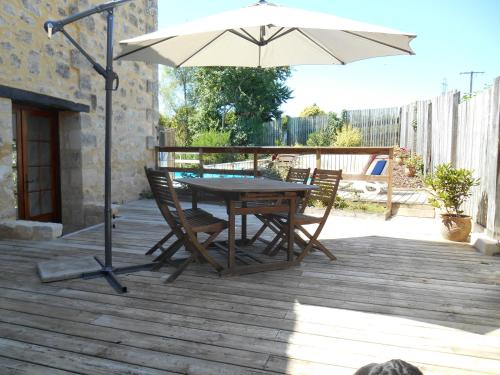 a table and chairs with an umbrella on a deck at Sous les Marronniers in Petit-Palais-et-Cornemps