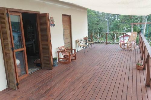a porch with a wooden deck with chairs and a table at Morada da Serra Alta in São Francisco de Paula