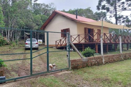 a house with a dog behind a fence at Morada da Serra Alta in São Francisco de Paula