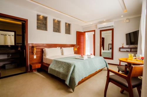 a bedroom with a bed and a table and a desk at AWARA POUSADA BOUTIQUE in São Miguel do Gostoso