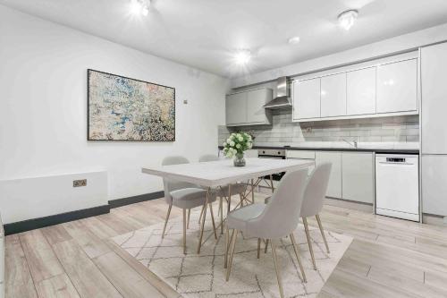 a white kitchen with a dining room table and chairs at Cozy London Apartment in London