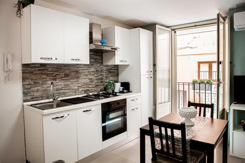 une petite cuisine avec des placards blancs et une table avec une salle à manger dans l'établissement Ruggero Settimo - Holiday Houses, à Catane