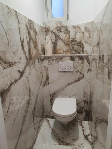 a marble bathroom with a toilet and a window at VIENNA Premium Apartments - self check-in in Vienna